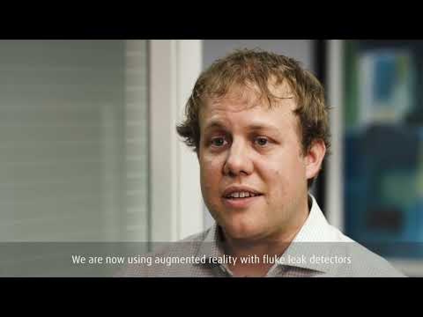 A man with curly blond hair and a light-colored shirt speaks in an office. The caption reads: Were now using augmented reality with Fluke leak detectors.